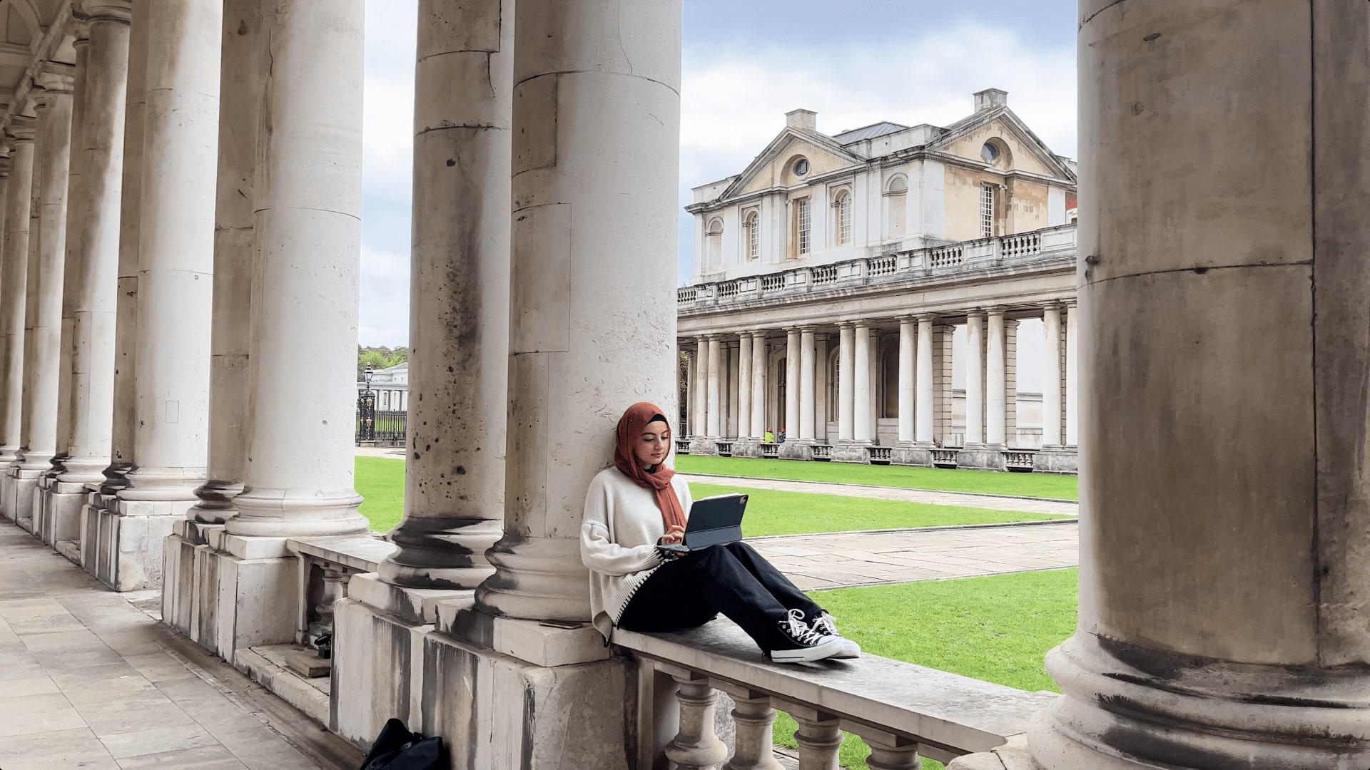 Jasmine sitting outside on campus using a tablet