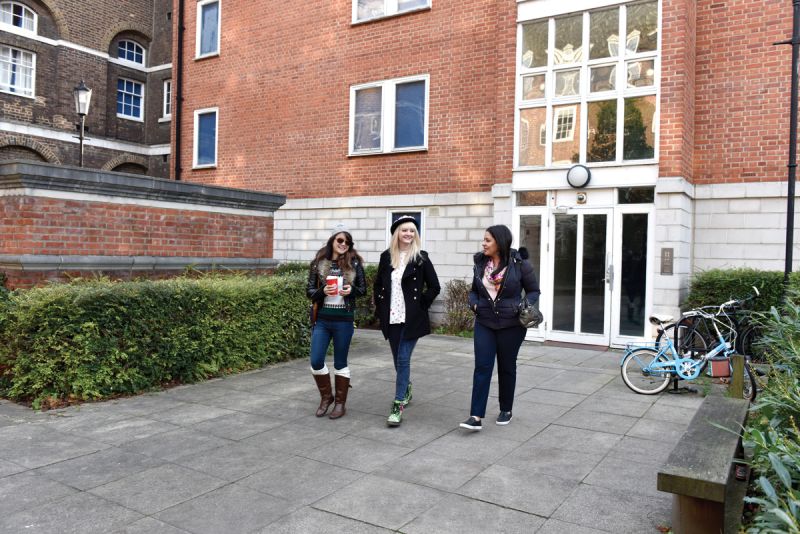 Three students walking across Devonport House courtyard