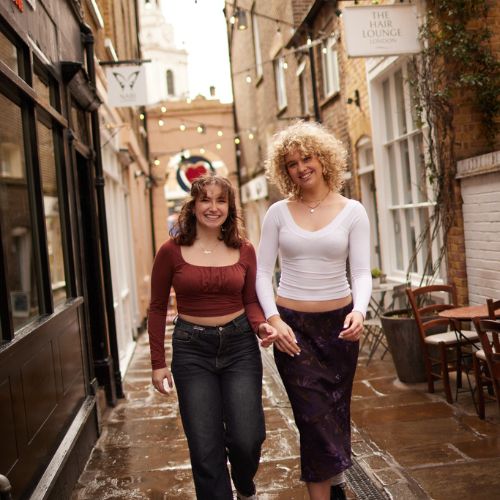 Two women walking down an alleyway into the centre of Greenwich Market